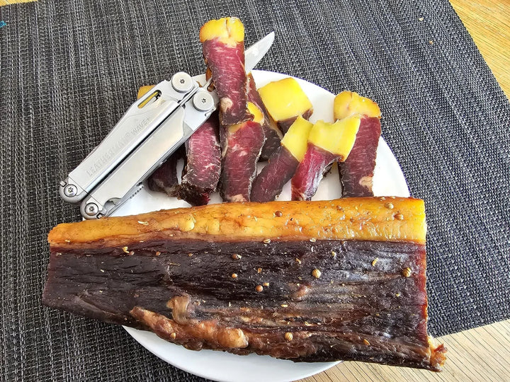 Geelvetbiltong en gesnyde happies op ’n bord.