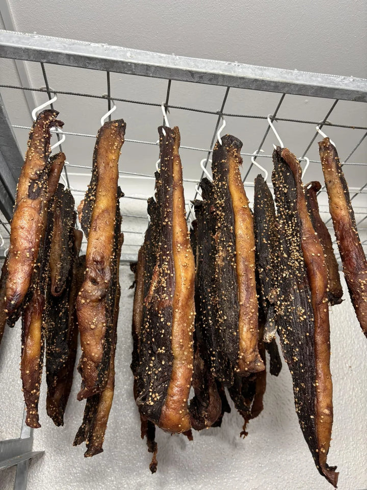 Lang stukke biltong wat aan ’n rak hang.