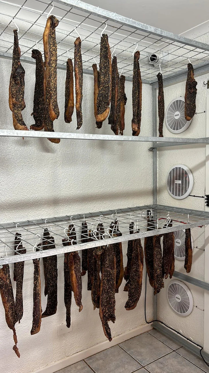 Verskeie vlakke hangende biltong in ’n droogruimte.