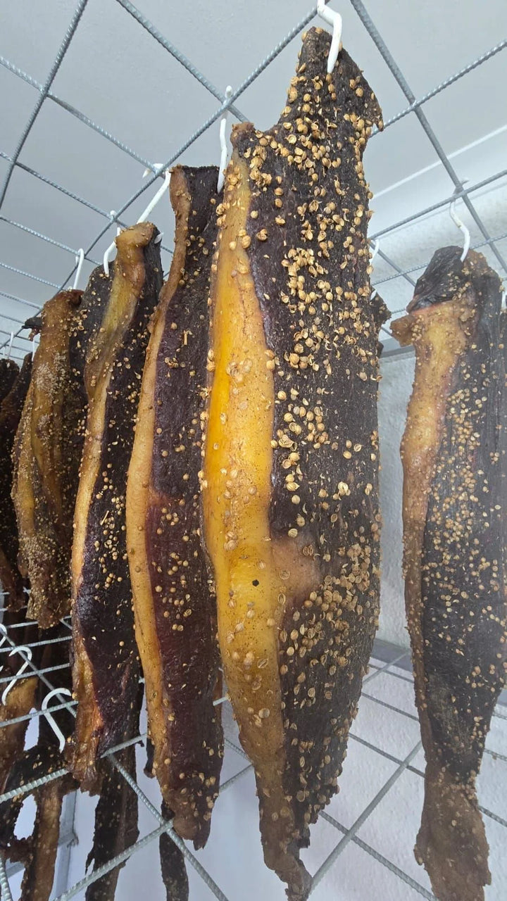 Gekruide biltong met geelvet wat aan hake hang.