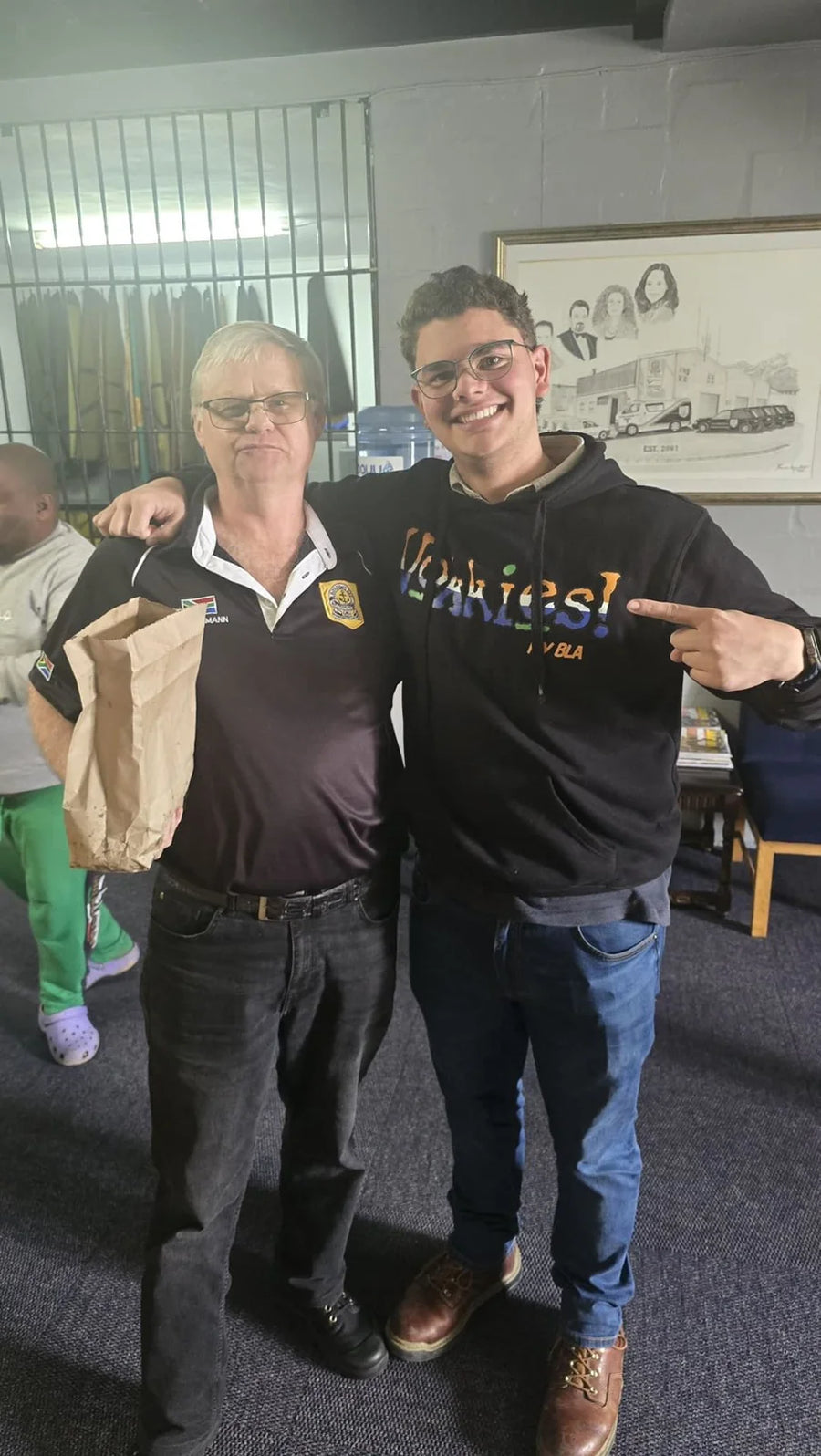 Twee mense in Vokkies-hemde poseer in die winkel.